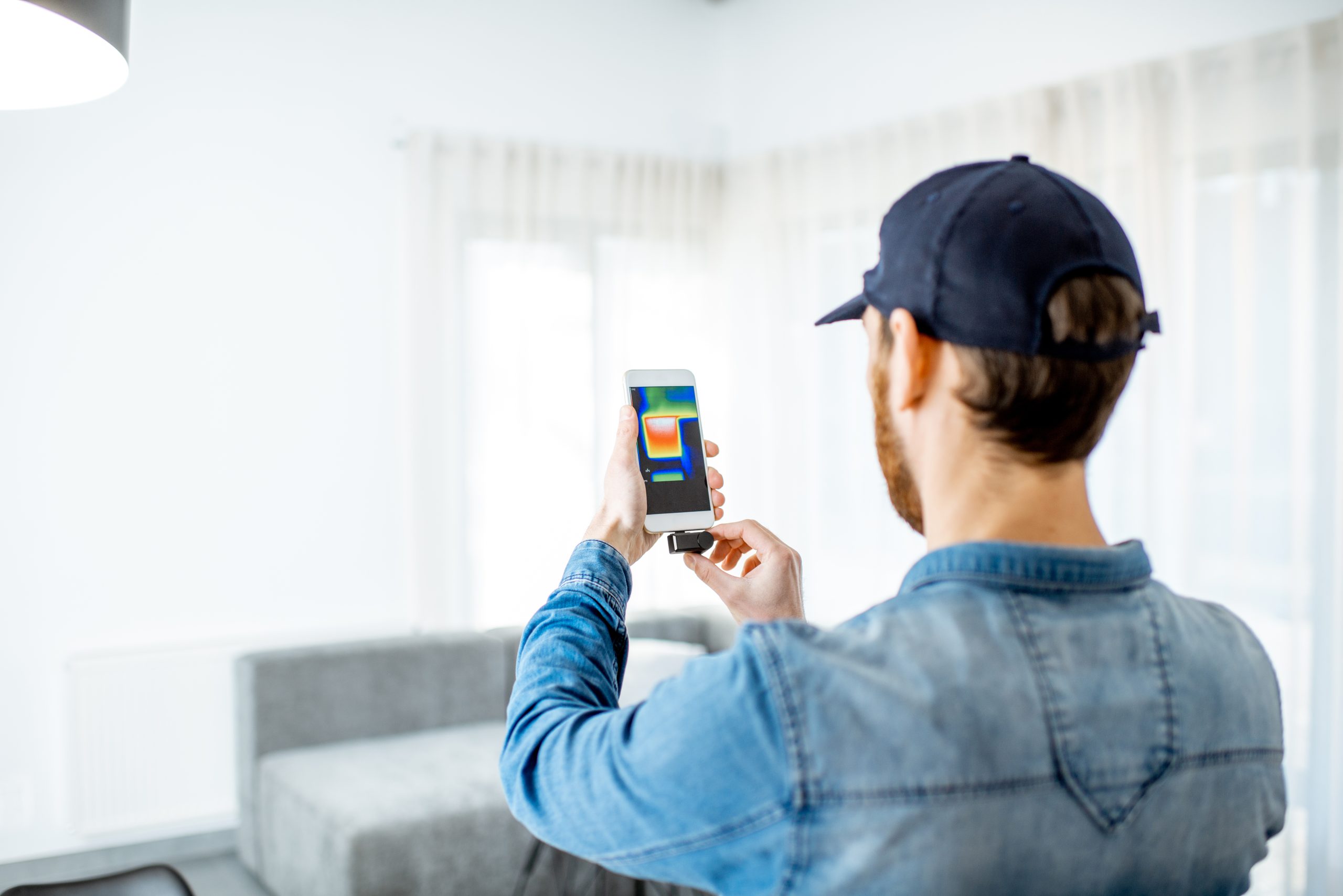 man checking the house heat loss with thermovision camera indoors